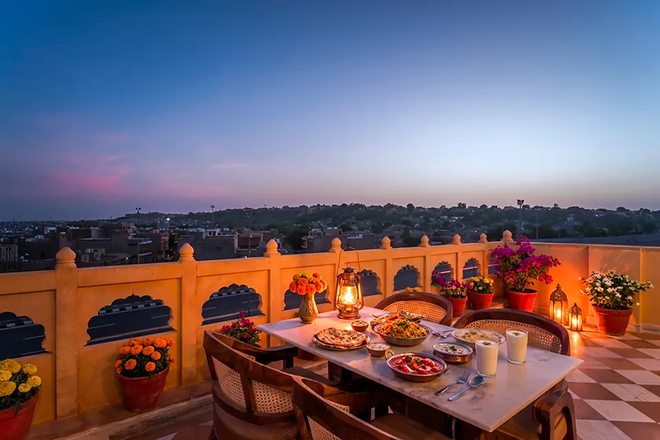 Candlelit dinner table on the rooftop terrace at dusk, Jaisalmer